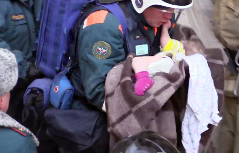 This handout picture released by The Russian Emergency Situations Ministry on Jan. 1, 2019, shows emergency officers transporting a baby surviver after a gas explosion rocked a residential building in Russia's Urals city of Magnitogorsk.