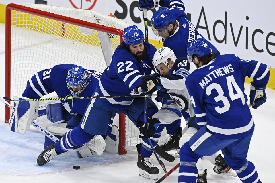 Toronto Maple Leafs goaltender Frederik Andersen (31) looks for the puck as Winnipeg Jets center Trevor Lewis (23) is surrounded by Maple Leafs' Zach Bogosian (22), Travis Dermott (23) and Auston Matthews (34) during first-period NHL hockey game action in Toronto, Saturday, March 13, 2021. (Frank Gunn/The Canadian Press via AP)