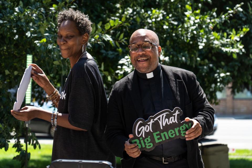Christ the King Catholic School secretary Nicole Archibald and Father John McKenzie move around as a camera spins around them recording a video during the Community Resource Fair at Christ the King Catholic School in Detroit on Aug. 18, 2023.