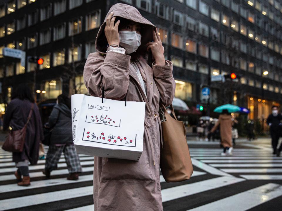 A woman wearing a face mask crosses a road on in Tokyo, Japan (Yuichi Yamazaki/Getty Images)