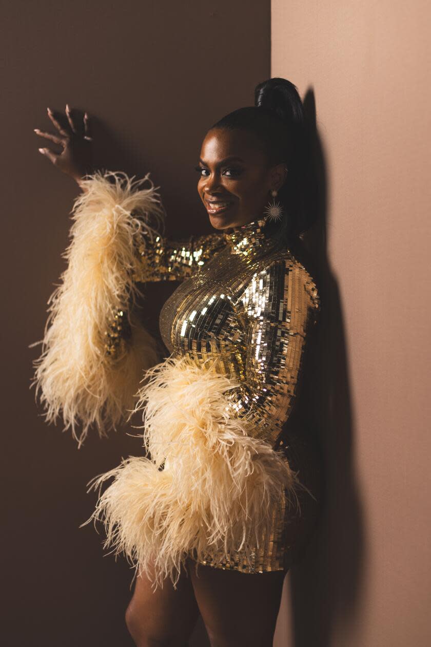 Kandi Burruss in a sparkly silver dress with feathery cuffs at her wrists.