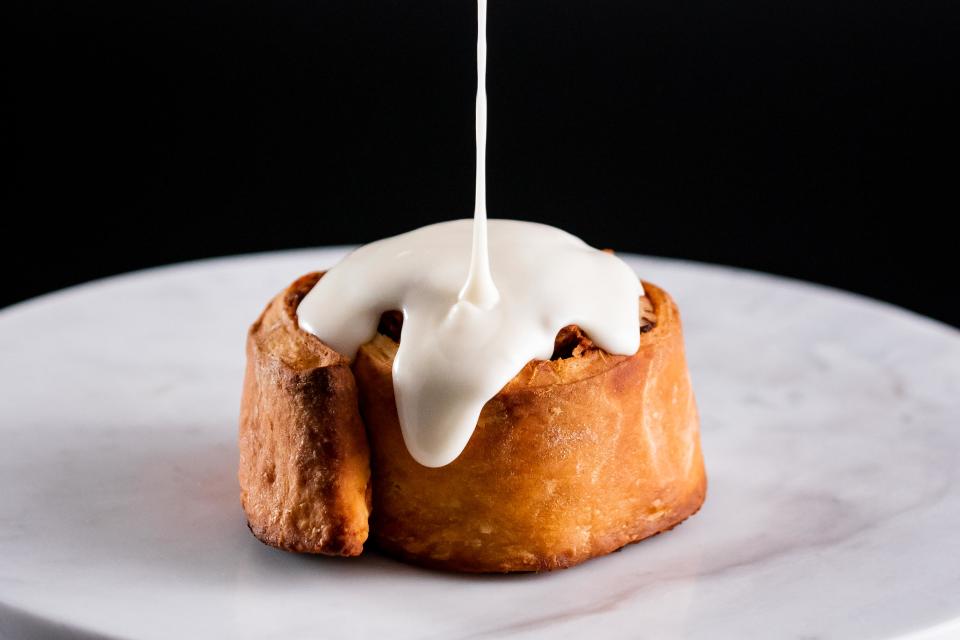 Sweet potato pecan roll with frosting pour close-up.