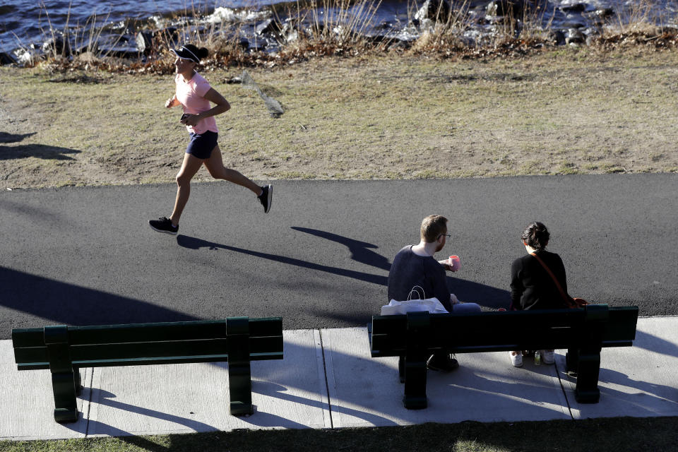 A runner makes her way along a path near the Charles River in the Charles River Esplanade park, in Boston, Sunday, Jan. 12, 2020, during unseasonably warm weather. Temperatures climbed into the low 70s in many places in the state Sunday. (AP Photo/Steven Senne)