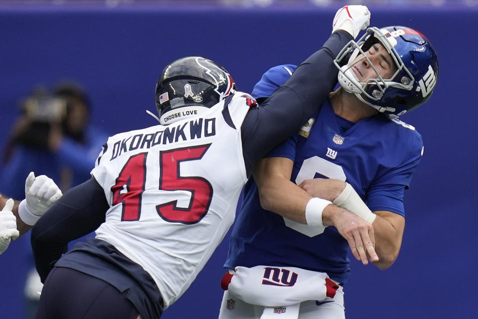 New York Giants quarterback Daniel Jones (8) takes a hit from Houston Texans linebacker Ogbonnia Okoronkwo (45) as he passes during the first quarter of an NFL football game, Sunday, Nov. 13, 2022, in East Rutherford, N.J. (AP Photo/Seth Wenig)