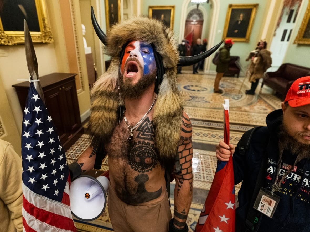 Jacob Anthony Chansley, centre, with other insurrectionists who supported then-President Donald Trump, are confronted by U.S. Capitol Police in the hallway outside of the Senate chamber in the Capitol on Jan. 6, 2021, in Washington. Chansley was among the first group of insurrectionists who entered the hallway outside the Senate chamber. (Manuel Balce Ceneta/Associated Press - image credit)