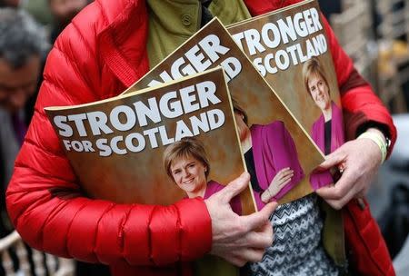 A supporter of the Scottish National Party (SNP) holds copies of their election manifesto at it's launch in Edinburgh, Scotland, April 201, 2015. REUTERS/Russel Cheyne