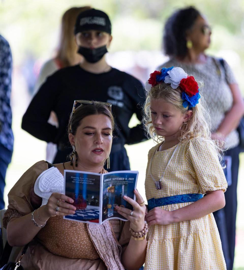 Nicole Caruso y su hija, Cecilia Caruso, de 8 años, leen un folleto informativo antes de la ceremonia de tributo a las víctimas de los ataques terroristas del 11 de septiembre de 2001, en Tropical Park, Miami, el domingo 11 de septiembre de 2022.