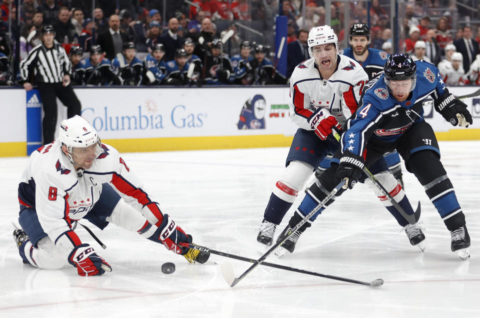 Columbus Blue Jackets defenseman Vladislav Gavrikov, right, reaches for the puck in front of Washington Capitals forward Alex Ovechkin, left, and forward Conor Sheary during the first period of an NHL hockey game in Columbus, Ohio, Tuesday, Jan. 31, 2023. (AP Photo/Paul Vernon)