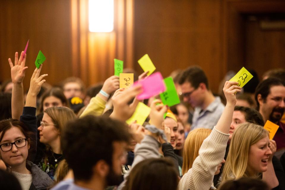 University of Iowa students hold up numbered cards while they caucus in 2020.