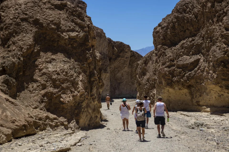 Hikers turn back to their vehicles in Golden Canyon on Tuesday, July 11, 2023, in Death Valley National Park, Calif. July is the hottest month at the park with an average high of 116 degrees (46.5 Celsius). (AP Photo/Ty ONeil)