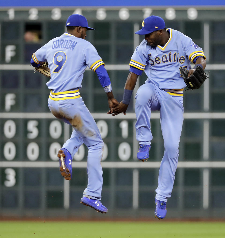 Seattle Mariners' Dee Gordon (9) and Guillermo Heredia celebrate after the Mariners' 5-2 win in a baseball game against the Houston Astros on Friday, Aug. 10, 2018, in Houston. (AP Photo/David J. Phillip)