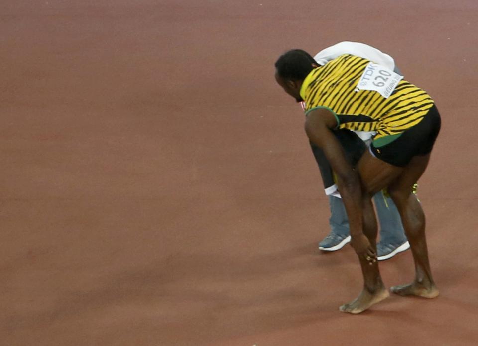 Winner Usain Bolt of Jamaica rubs his foot after being hit by a cameraman on a Segway (not pictured) after competing at the men's 200 metres final during the 15th IAAF World Championships at the National Stadium in Beijing, China, August 27, 2015. REUTERS/Kim Kyung-Hoon