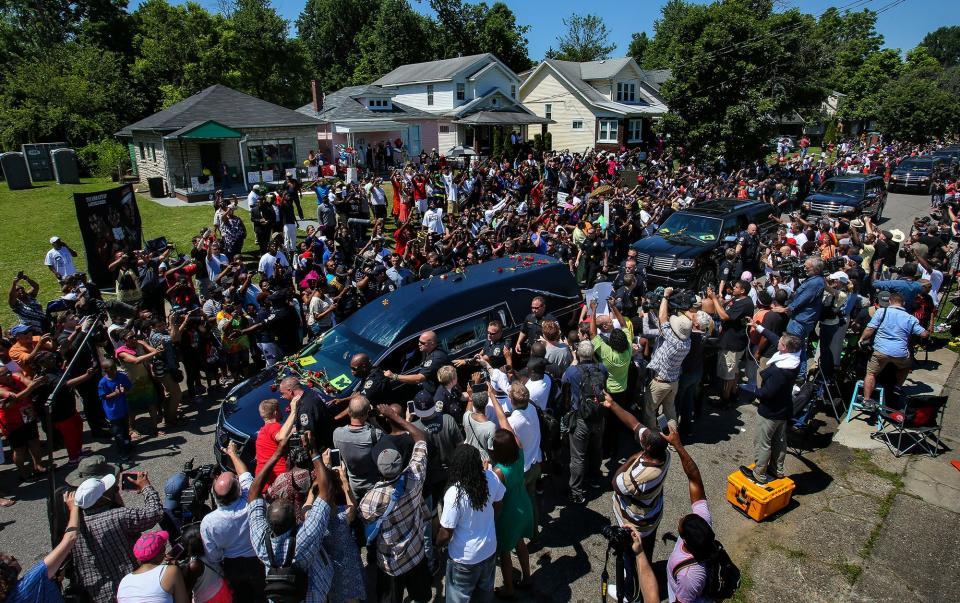 The funeral procession for Muhammad Ali makes its way past his boyhood home on Grand Avenue in Louisville as hundreds of fans line the streets Friday. June 10, 2016