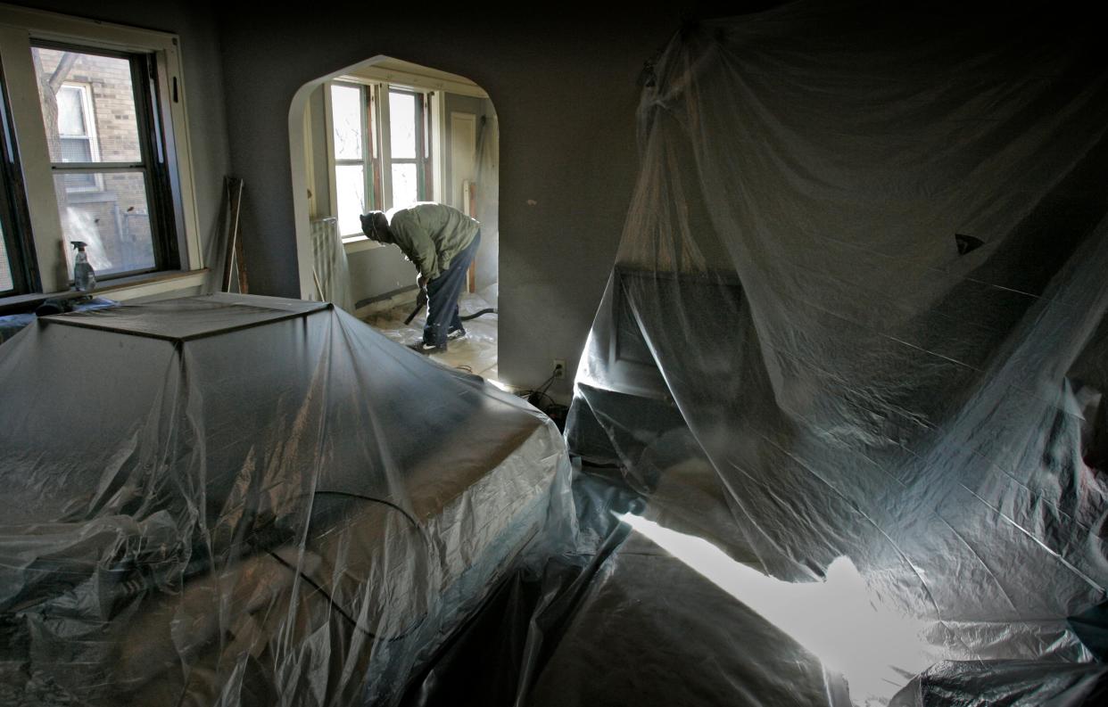 A worker vacuums lead paint chips from a building in the 1400 block of North 21st Street as part of a City of Milwaukee lead abatement program.