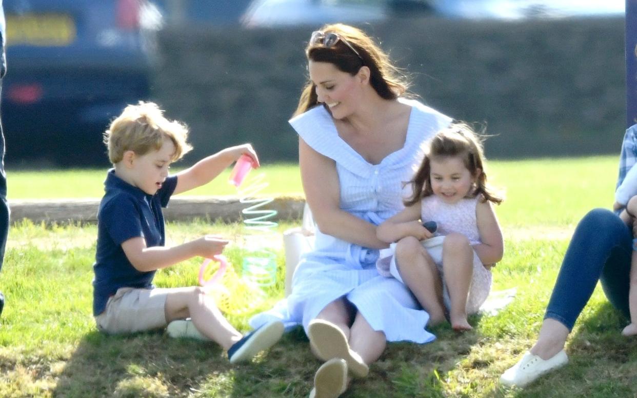 Princess Charlotte gets a cuddle from the Duchess of Cambridge while Prince George plays with a Slinky - WireImage