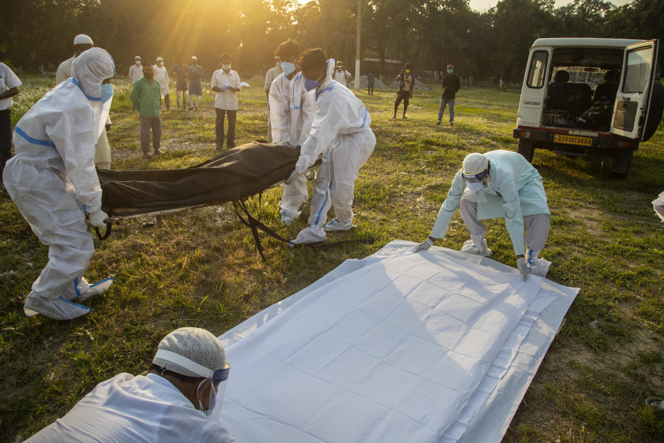 FILE - In this April 25, 2021, file photo, municipal workers prepare to bury a person who died of COVID-19 in Gauhati, India. Despite clear signs that India was being swamped by another surge of coronavirus infections, Prime Minister Narendra Modi refused to cancel campaign rallies, a major Hindu festival and cricket matches with spectators. The crisis has badly dented Modi’s carefully cultivated image as an able technocrat. (AP Photo/Anupam Nath, File)