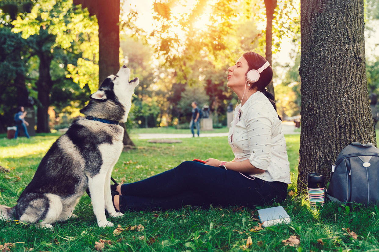 Girl with dog spending time in the park enjoying good music Getty Images/martin-dm
