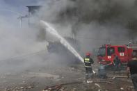 Firefighters extinguish flames as smoke rises from Surmalu market about two kilometers (1.2 miles) south of the center Yerevan, Armenia, Sunday, Aug. 14, 2022. A strong explosion at a fireworks storage area has ripped through a market in Armenia's capital. At least one person has been killed and about 20 others have been injured. The blast on Sunday set off a large fire. (Vahram Baghdasaryan/Photolure via AP)