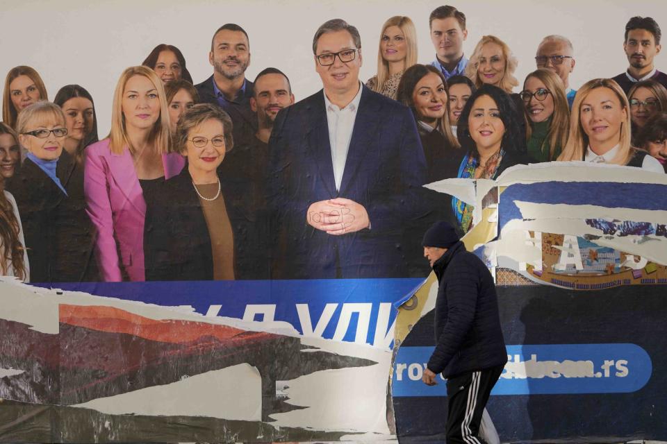 A man walks past a damaged pre-election billboard showing Serbian President Aleksandar Vucic with members of his ruling Serbian Progressive Party in Belgrade, Serbia, Monday, Dec. 18, 2023. An early official vote count of Serbia's weekend election on Monday confirmed victory for the ruling populist party in a parliamentary vote in the Balkan country, but political tensions rose over reported irregularities in the capital, Belgrade. (AP Photo/Darko Vojinovic)