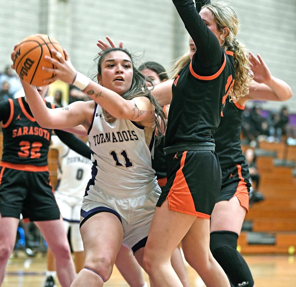 Booker's Annette Castro (#11) pulls down a rebound against Sarasota's Kennedy McClain (#10). Booker took a two point lead in the last 38.4 seconds of remaining regulation play winning 56-54 Thursday night at Booker's Tornado Alley in Sarasota.