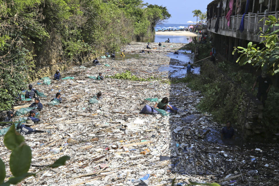 Environmental activists and volunteers pick up trash from a garbage-strewn river during a river cleanup event in Pecatu, Bali, Indonesia on Friday, March 22, 2024. (AP Photo/Firdia Lisnawati)