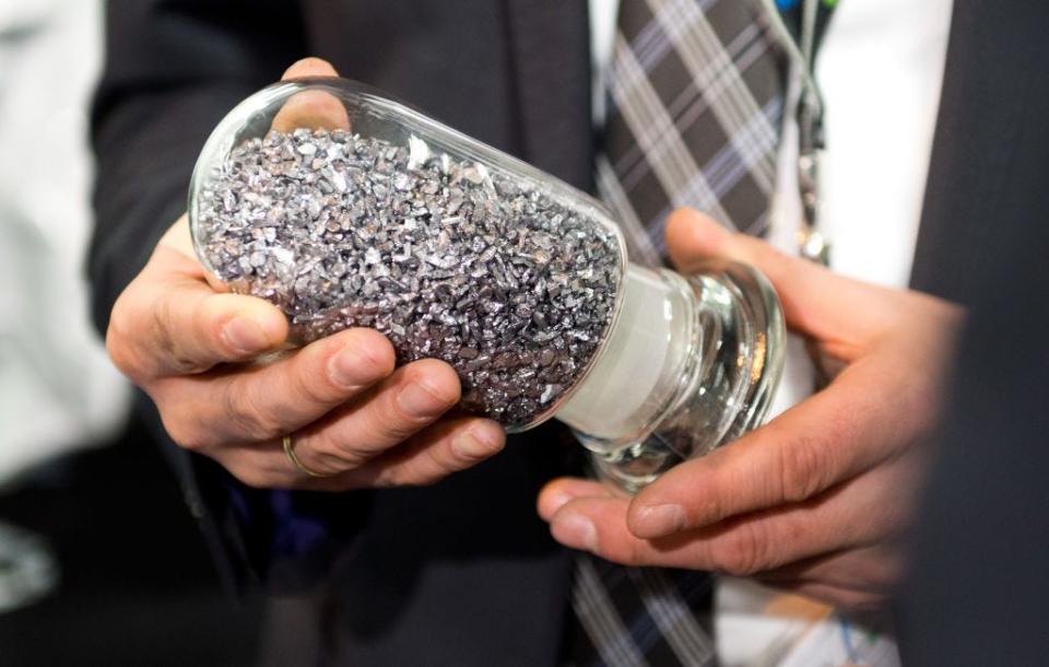 A man holds a tungsten sample in a glass jar