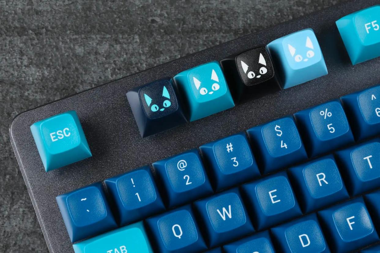  Four cat themed keycaps on a keyboard. 