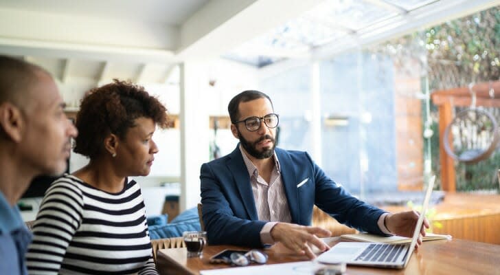 A couple speaks with their financial advisors. President Joe Biden wants to raise the long-term capital gains tax rate for the wealthiest Americans.