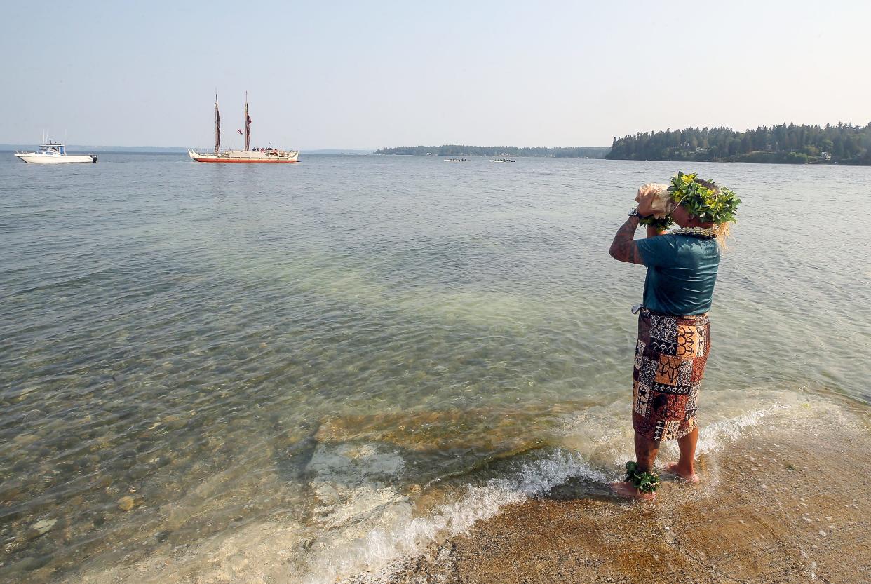 Keoni Sabal Keliiholokai, of Poulsbo, blows a conch shell from the shore of Suquamish as the traditional Polynesian Voyaging Canoe Hōkūleʻa is granted permission to land in Suquamish on Aug. 24.