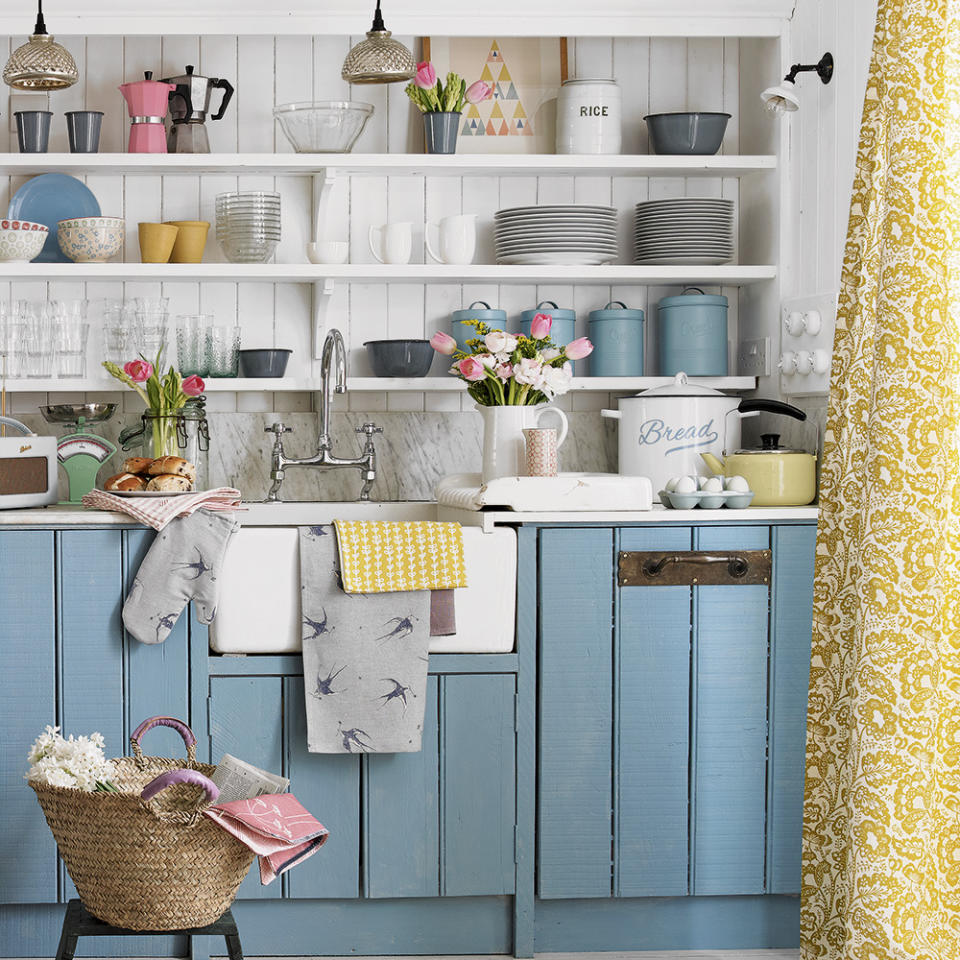 blue painted cupboards in kitchen with white panelled wall and open display shelves