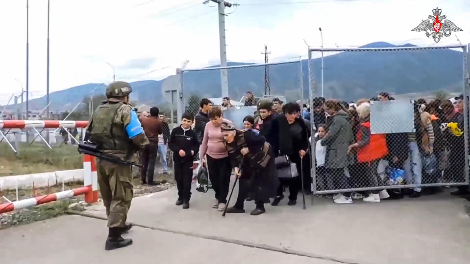 In this image made from video released by Russian Defense Ministry Press Service on Thursday, Sept. 21, 2023, a Russian peacekeeper guards a gate into a camp near Stepanakert in Nagorno-Karabakh. Thousands of Nagorno-Karabakh residents flocked to a camp operated by Russian peacekeepers to avoid the fighting, while many others gathered at the airport of the regional capital, Stepanakert, hoping to flee the region. (Russian Defense Ministry Press Service via AP)