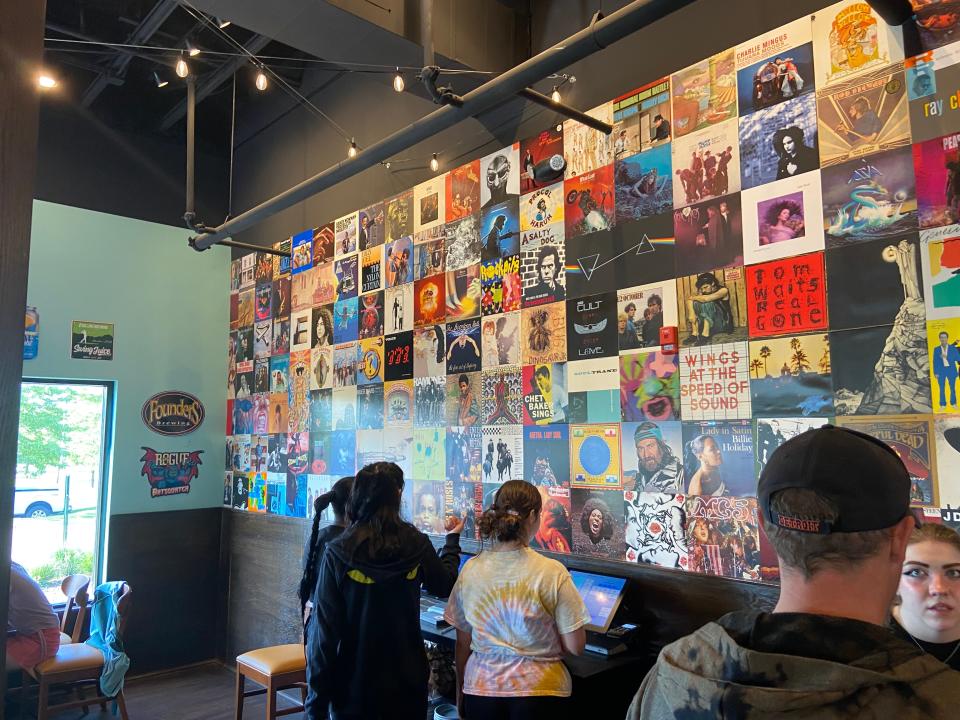 Album covers line a large wall inside HopCat Livonia.