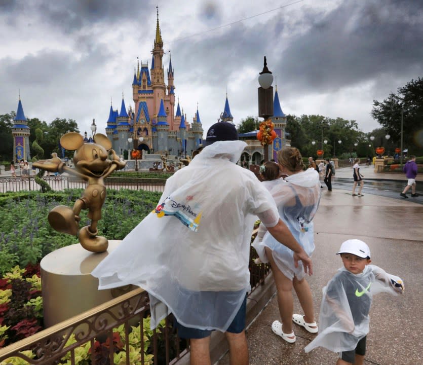 A family braves the rain as bands of rain from Hurricane Idalia move through the Magic Kingdom at Walt Disney World, in Lake Buena Vista, Fla., Wednesday, Aug. 30, 2023. All four of Disney’s Florida theme parks operated with normal hours as Idalia’s main impact was further north in the Big Bend area of the state. (Joe Burbank/Orlando Sentinel via AP)