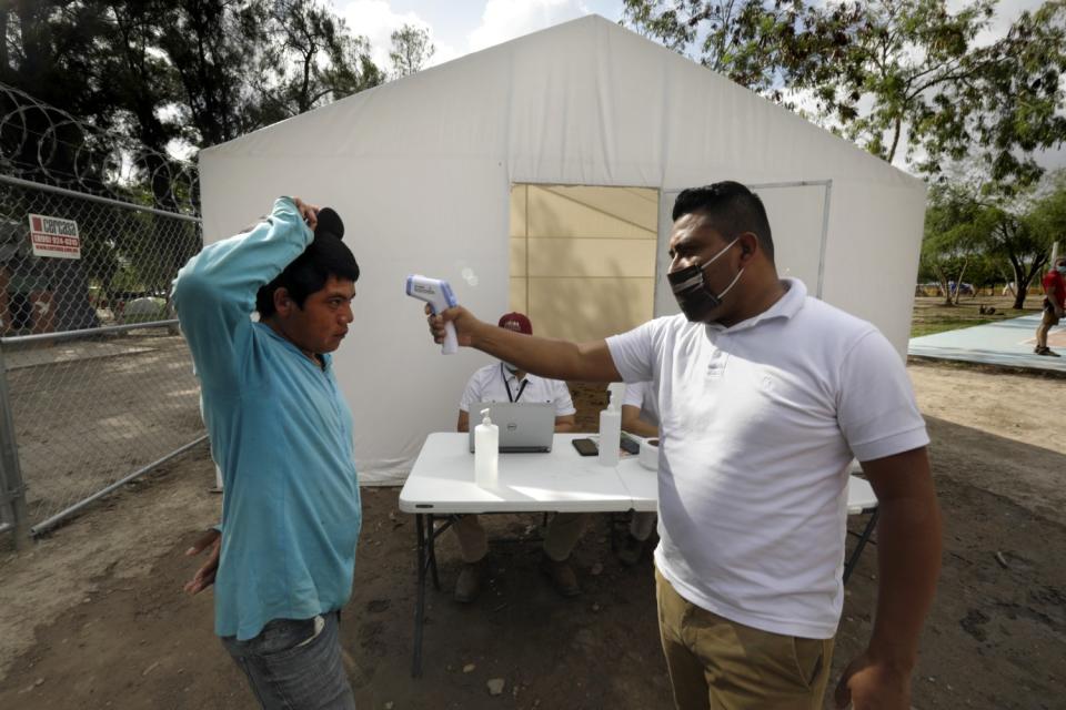 A man has his temperature taken at the camp in Matamoros, Mexico.