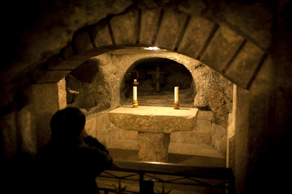 In this Tuesday Dec. 10, 2013 photograph, a tourist prays in the Grotto underneath the Church of the Nativity in the West Bank city of Bethlehem. To visitors arriving in Bethlehem for Christmas this year the Nativity Church will look different. Wrapped in scaffolding, the basilica is having a much-needed facelift after 600 years. Last year it has been included in UNESCO's list of endangered World Heritage sites. (AP Photo/Nasser Nasser)