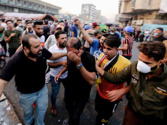 A wounded Iraqi demonstrator rushes towards an ambulance during clashes with Iraqi forces in al-Khalani square (AFP via Getty)