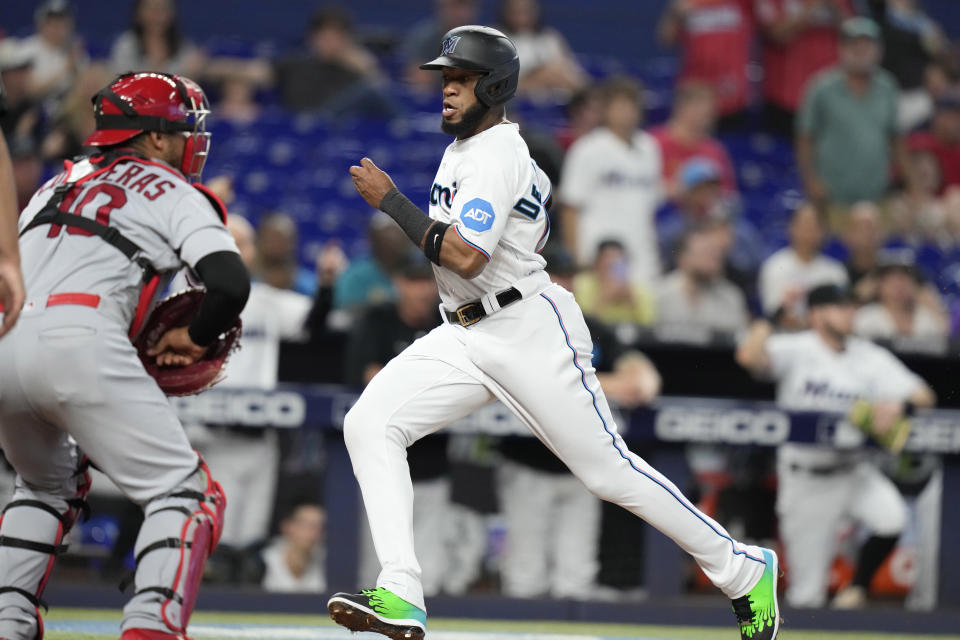 Miami Marlins' Bryan De La Cruz, right, runs home to score past St. Louis Cardinals catcher Willson Contreras on a double hit by Garrett Cooper during the first inning of a baseball game Wednesday, July 5, 2023, in Miami. (AP Photo/Lynne Sladky)