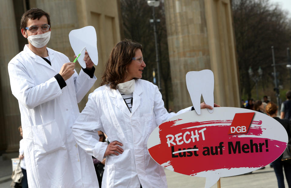 Two demonstrators posing as unequally paid dentists, the woman holding a sign reading 'Not a Wish But a Right to More!', demonstrate during the 'Equal Pay Day' demonstration on March 21, 2014 in Berlin. (Photo: Adam Berry via Getty Images)