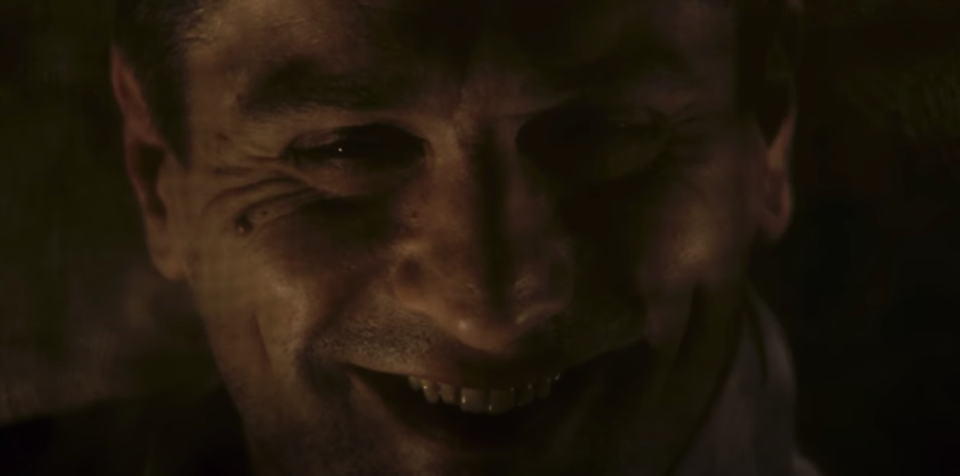 A man smiles a sinister smile