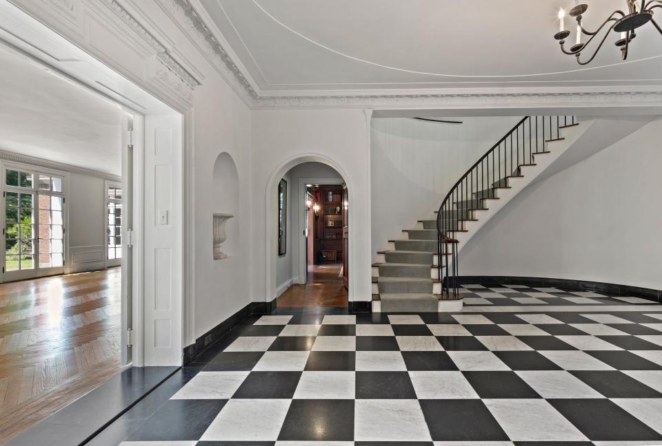 The entry hall features a black and white marble floor and a floating curved staircase.