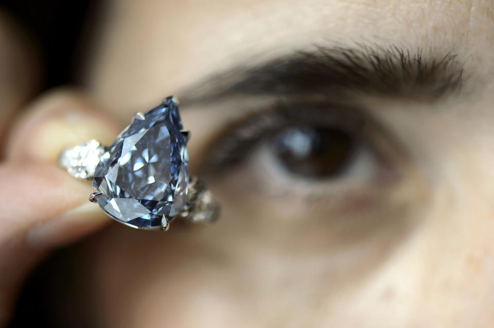 FILE - In this May 9, 2014 file picture a Christie's employee holds a 13.22 carat diamond called 'The Blue', the largest flawless vivid blue diamond yet found, which is estimated to sell between US dlrs 21 to 25 million , during a preview at Christie's, in Geneva, Switzerland. The auction will take place on Wednesday May 14, 2014 evening in Geneva. (AP Photo/Keystone, Martial Trezzini,file)