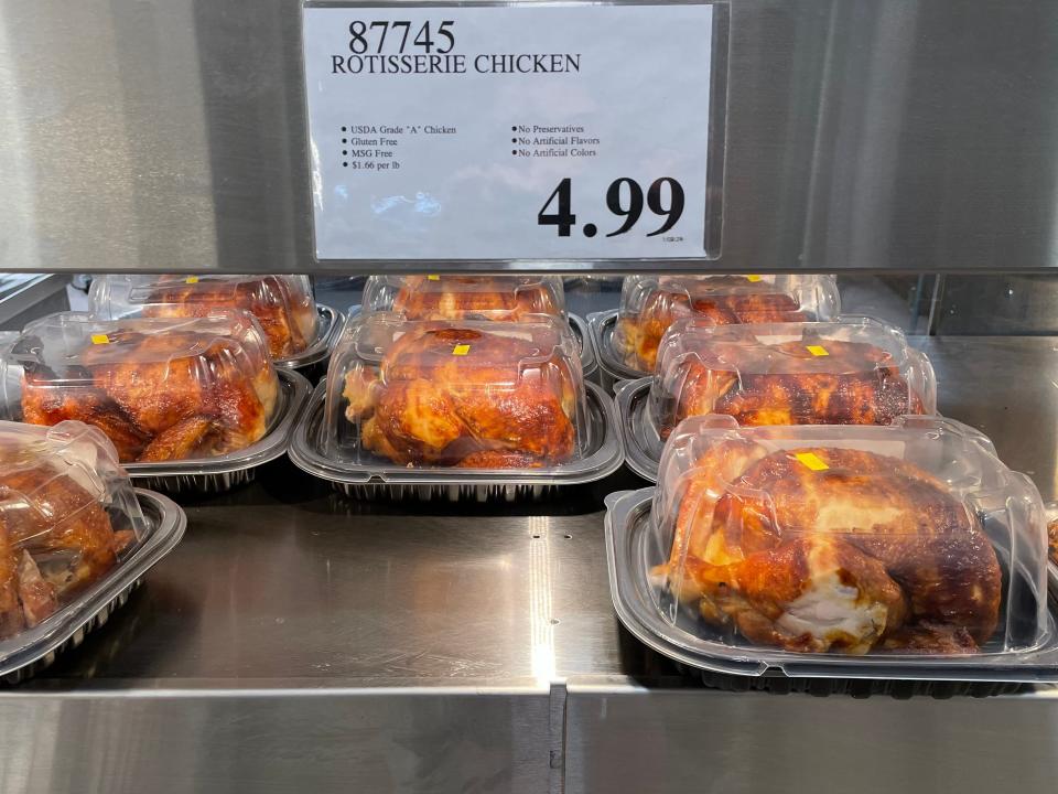 Several rotisserie chickens in clear plastic containers with a $4.99 sign above the chicken