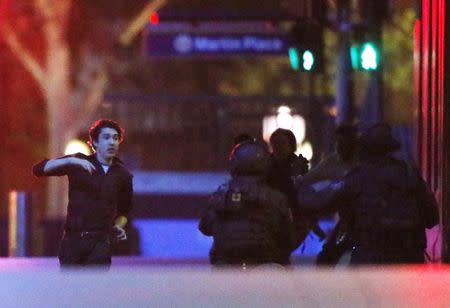 A hostage (L) runs towards police officers near Lindt Cafe, at Martin Place in central Sydney December 16, 2014. REUTERS/Jason Reed