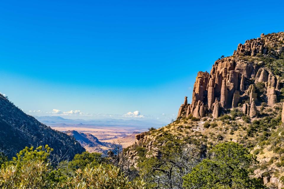 a rocky cliff with trees and blue sky