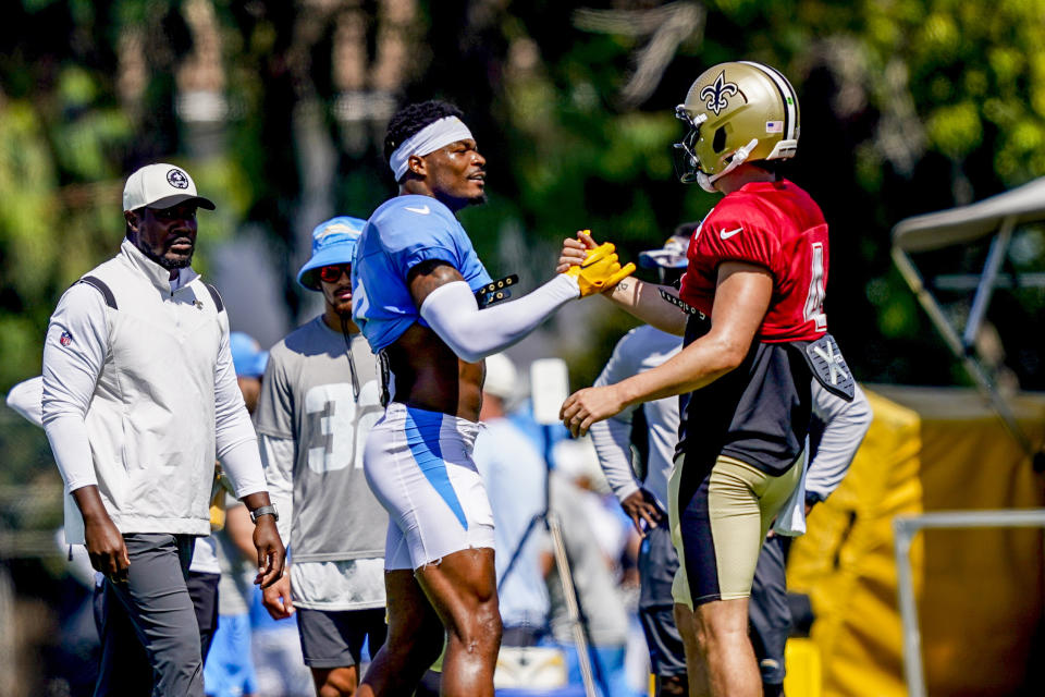 Los Angeles Chargers safety Derwin James Jr., center left, greets New Orleans Saints quarterback Derek Carr (4) during a joint NFL football practice, Thursday, Aug. 17, 2023, in Costa Mesa, Calif. (AP Photo/Ryan Sun)