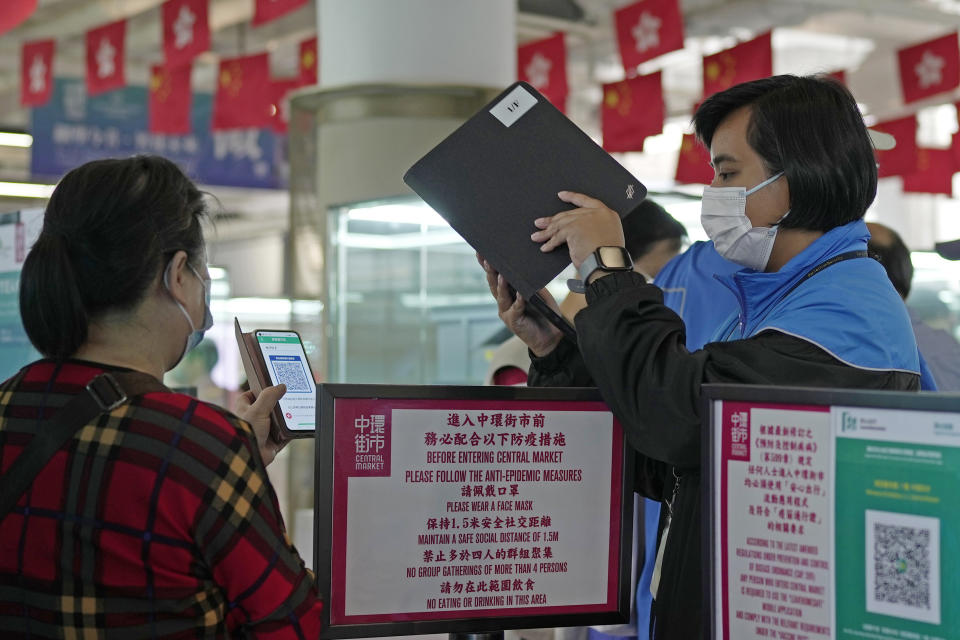 A woman scans a government's contact tracing QR code for the "LeaveHomeSafe" COVID-19 mobile app at a shopping mall in Hong Kong, Tuesday, July 12, 2022. Hong Kong's leader John Lee on Tuesday defended plans to introduce a new virus "health code" that would use mobile phones to classify people as "red" or "yellow" and limit their movement. (AP Photo/Kin Cheung)