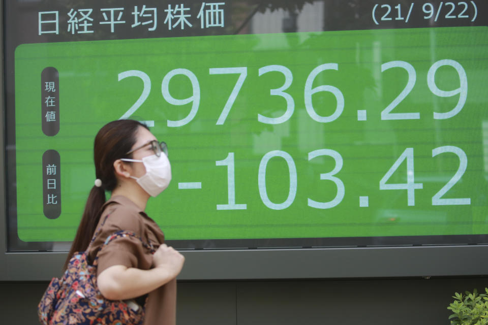 A woman walks by an electronic stock board of a securities firm in Tokyo, Wednesday, Sept. 22, 2021. Asian shares were mostly lower on Wednesday after major indexes ended mixed on Wall Street.(AP Photo/Koji Sasahara)