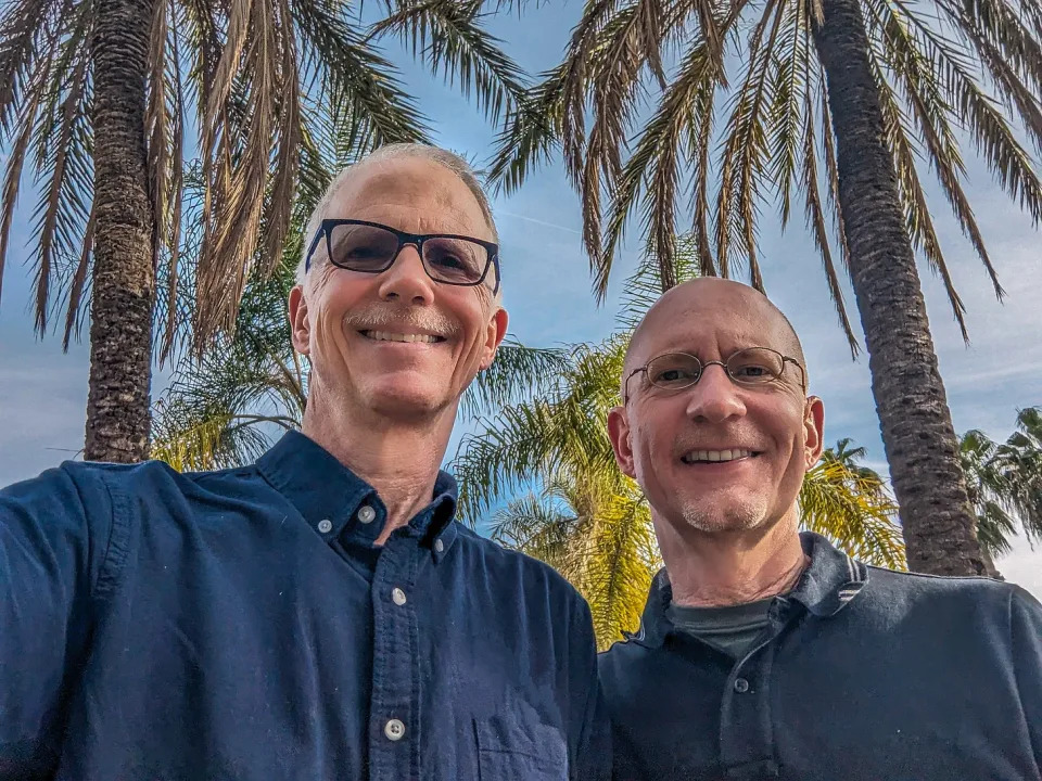 Brent and Michael standing in front of palm trees. 