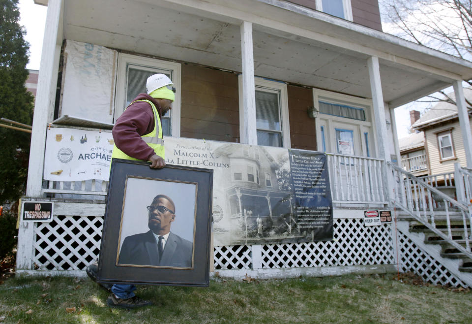 FILE - In this March 29, 2016, file photo, Rodnell P. Collins carries a painting of his uncle, Malcolm X outside the house where the slain African-American activist spent part of his teen years in the Roxbury neighborhood of Boston. According to the National Park Service the house was added to the National Register of Historic Places in February 2021. (AP Photo/Bill Sikes, File)