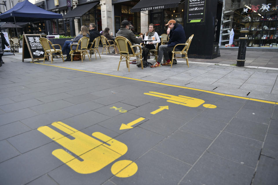 Customers sit in the outdoor seating of bars and cafes in Cardiff prior to Wales entering a "firebreak" lockdown, Friday, Oct. 23, 2020. A police force in England says it will try to stop people from leaving Wales, which has started a 17-day lockdown to slow the spread of COVID-19. The Gloucestershire Constabulary says it will patrol routes from Wales and pull over drivers they believe are making long journeys. Travelers without a good excuse will be asked to turn around. (Ben Birchall/PA via AP)